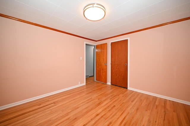 unfurnished bedroom featuring crown molding, a closet, and light wood-type flooring