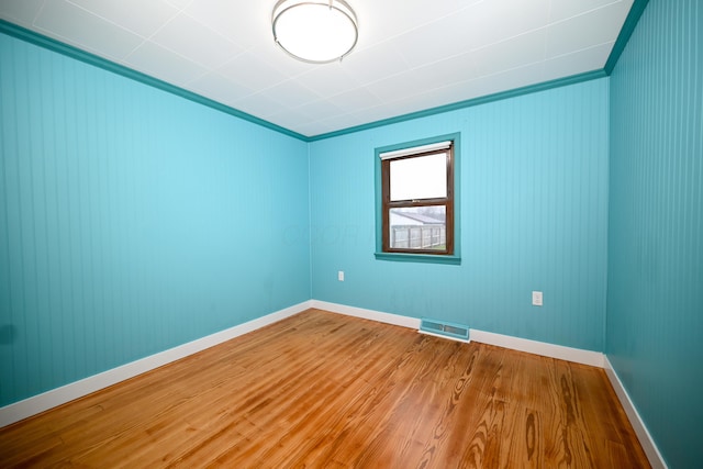 empty room featuring ornamental molding and wood-type flooring