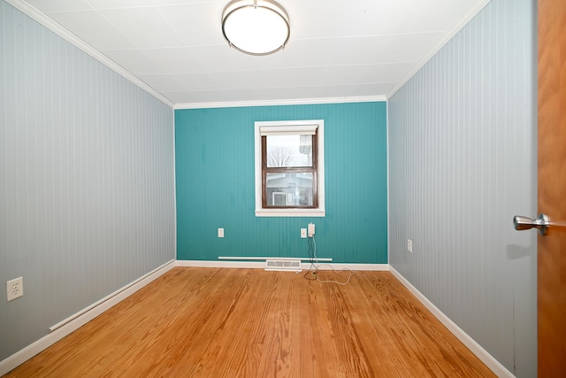 empty room with ornamental molding and light hardwood / wood-style floors