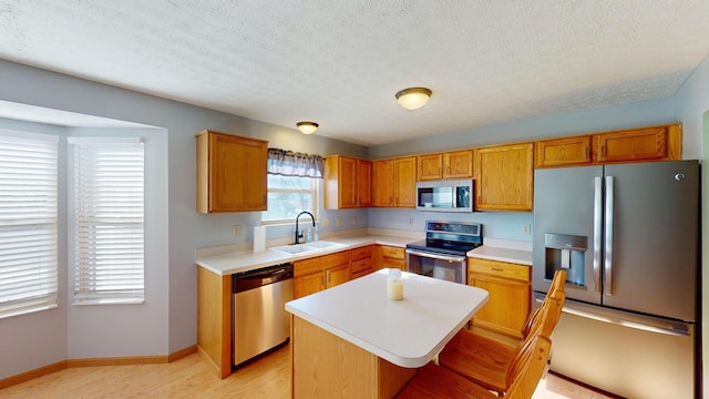 kitchen with a breakfast bar, a center island, sink, a textured ceiling, and stainless steel appliances