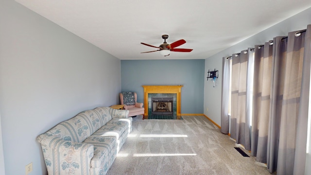 living room featuring ceiling fan, light carpet, and a tiled fireplace