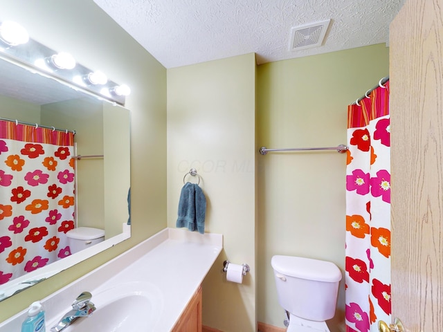 bathroom featuring vanity, a textured ceiling, toilet, and walk in shower