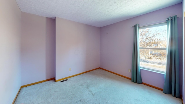 carpeted empty room featuring a textured ceiling