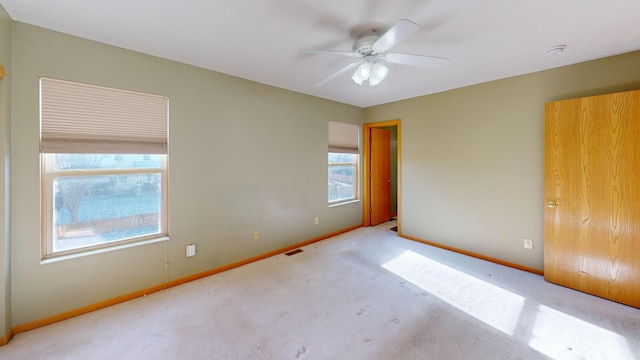 spare room with ceiling fan and light carpet