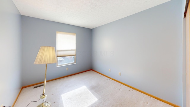 carpeted spare room with a textured ceiling