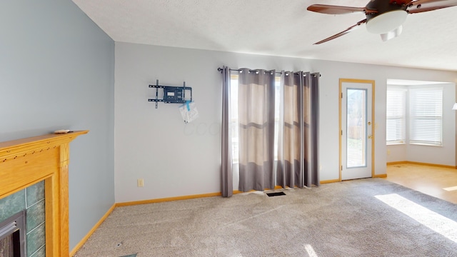 unfurnished living room featuring carpet, ceiling fan, a fireplace, and a textured ceiling