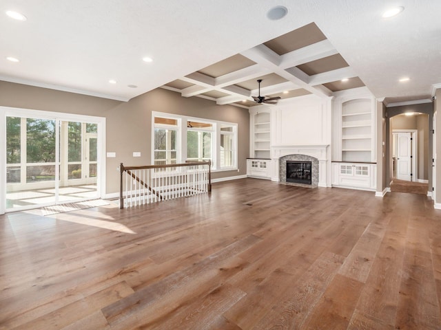 unfurnished living room with built in shelves, beam ceiling, a fireplace, ceiling fan, and coffered ceiling