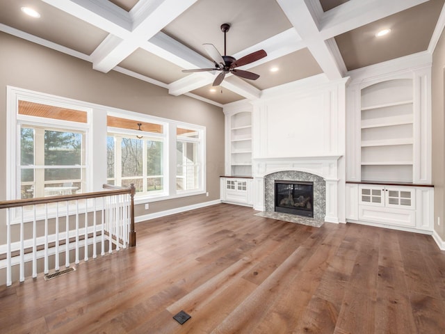 unfurnished living room featuring beamed ceiling, ceiling fan, hardwood / wood-style floors, a premium fireplace, and coffered ceiling