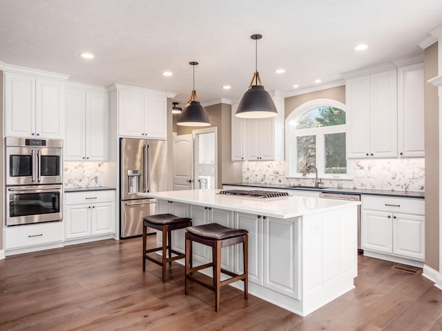 kitchen featuring sink, stainless steel appliances, a center island, and pendant lighting