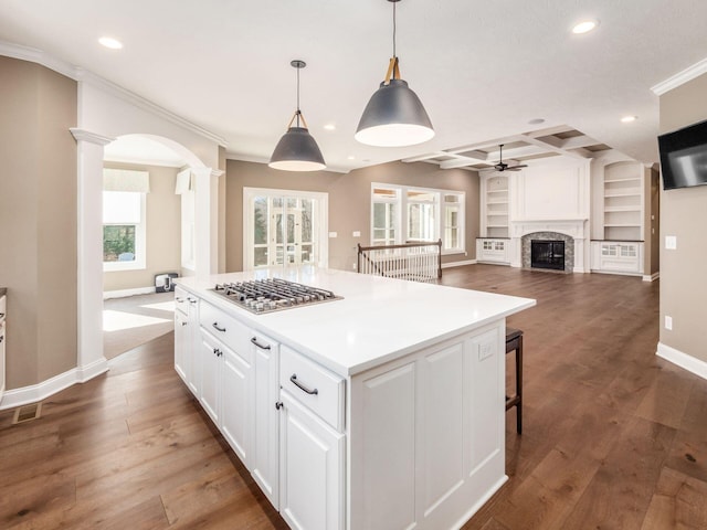 kitchen with coffered ceiling, stainless steel gas stovetop, a kitchen island, beam ceiling, and white cabinets