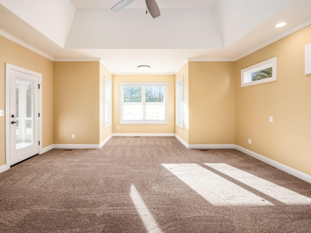 empty room with a raised ceiling, ceiling fan, carpet, and crown molding