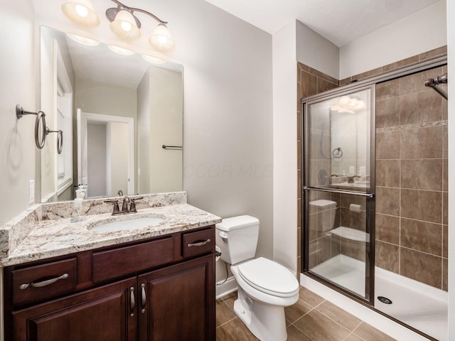 bathroom featuring toilet, tile patterned flooring, walk in shower, and vanity