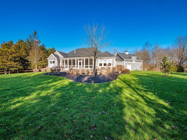 rear view of house featuring a yard and a sunroom