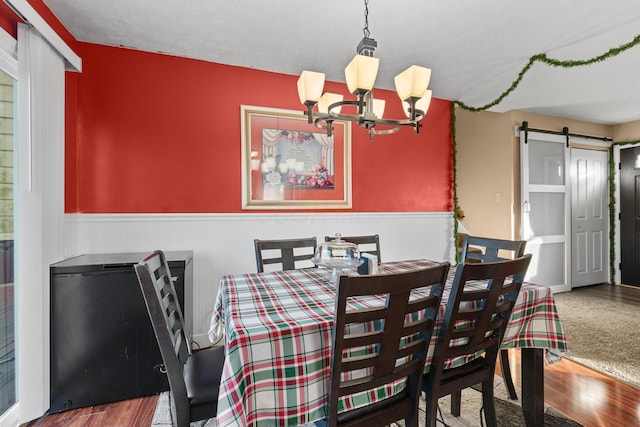 dining space with a chandelier, a textured ceiling, a barn door, and hardwood / wood-style flooring