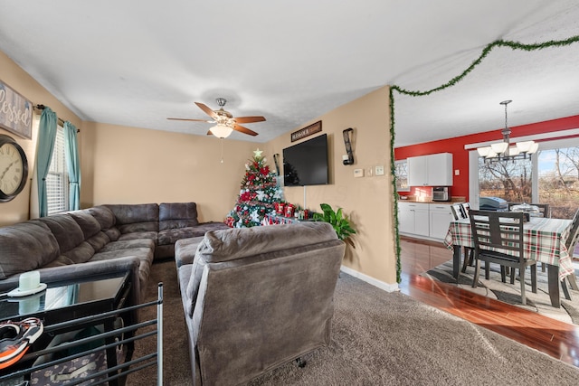 living room with ceiling fan with notable chandelier and dark hardwood / wood-style floors