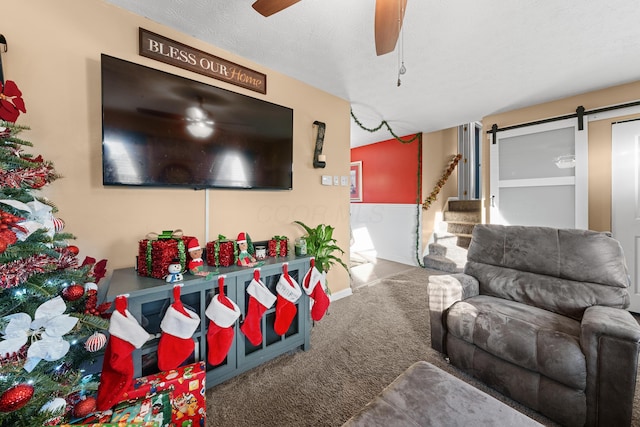 living room with a textured ceiling, a barn door, carpet floors, and ceiling fan