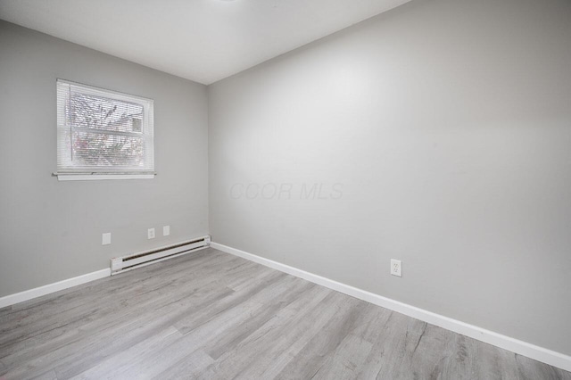 spare room with a baseboard radiator and light wood-type flooring