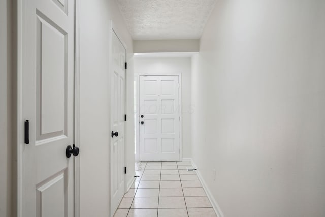 corridor featuring light tile patterned floors and a textured ceiling