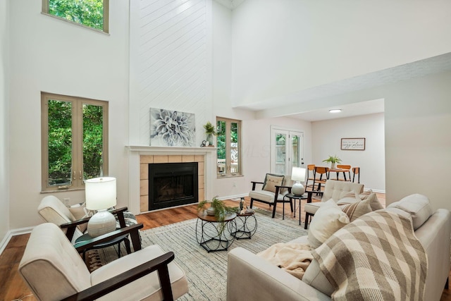 living room featuring hardwood / wood-style flooring, a towering ceiling, a fireplace, and a wealth of natural light