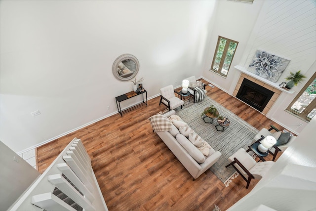 living room with hardwood / wood-style floors, a towering ceiling, and a tiled fireplace