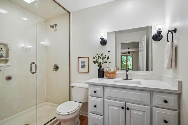 bathroom with ceiling fan, a shower with door, vanity, and toilet