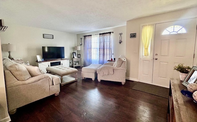 living room with a textured ceiling, dark hardwood / wood-style flooring, and a healthy amount of sunlight