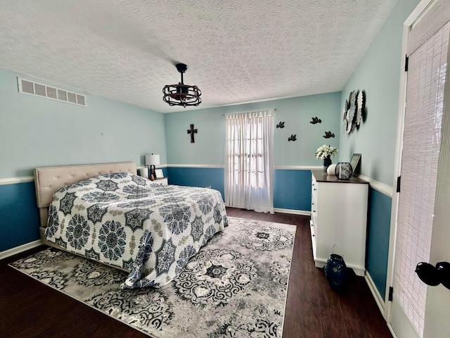 bedroom featuring a textured ceiling and dark hardwood / wood-style flooring