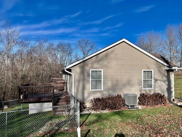 view of side of property with central AC unit, a wooden deck, and a lawn