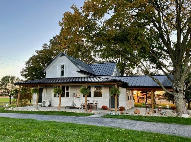 back of house with a lawn and covered porch