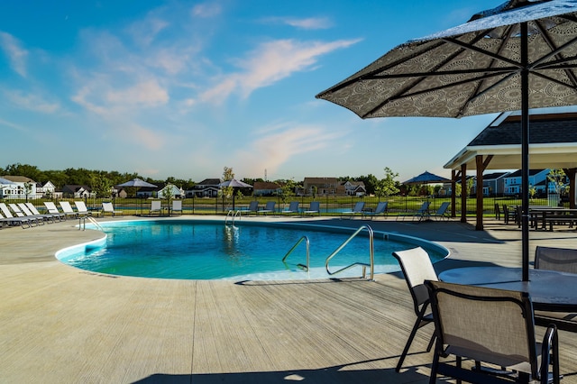 community pool with a patio area and fence