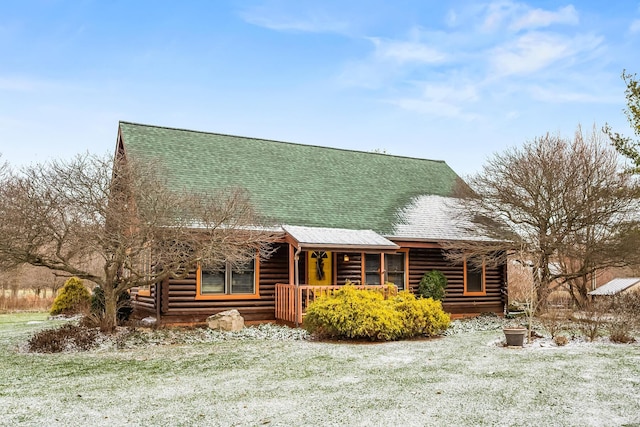 cabin with log siding, a porch, and roof with shingles