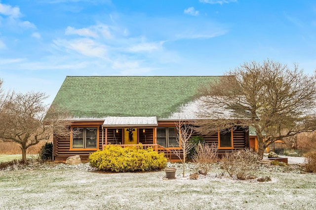 log cabin with a shingled roof, a porch, and log exterior