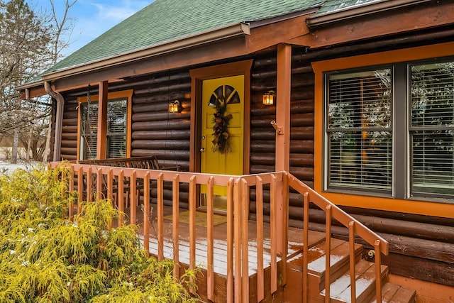 property entrance with a shingled roof and faux log siding