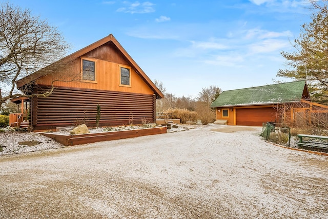 view of side of home with driveway, an outdoor structure, and log siding