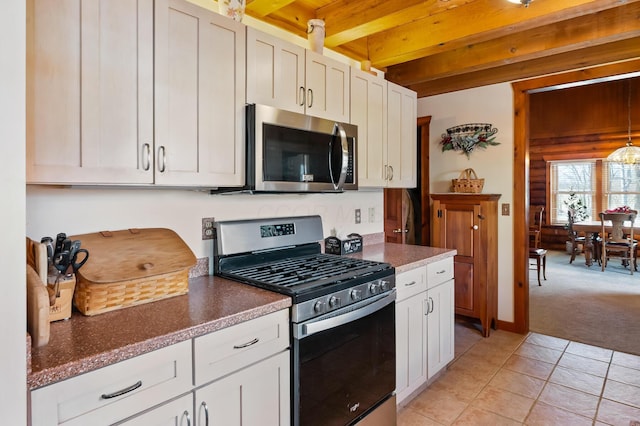 kitchen featuring white cabinets, stainless steel appliances, beam ceiling, and light colored carpet