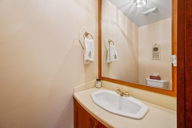 half bath featuring toilet, vanity, and visible vents