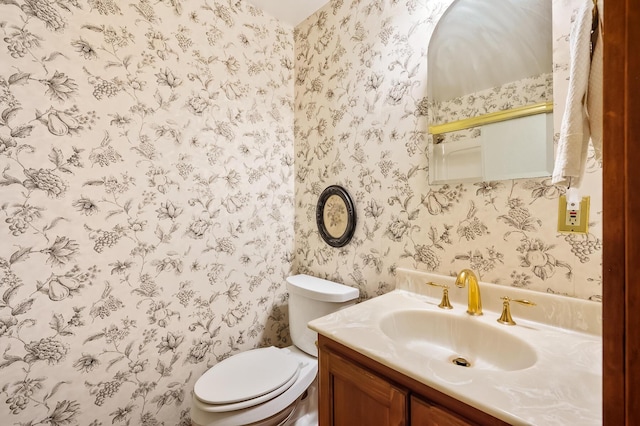 full bathroom with toilet, wallpapered walls, and vanity