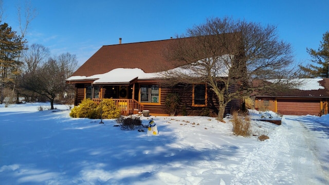 cabin with a garage, covered porch, and log siding