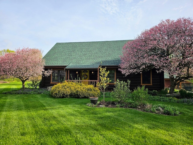 view of front of property with roof with shingles, a front lawn, and log siding