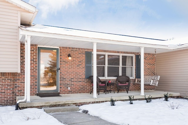 snow covered property entrance with covered porch