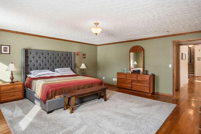 bedroom with crown molding, hardwood / wood-style flooring, and a textured ceiling