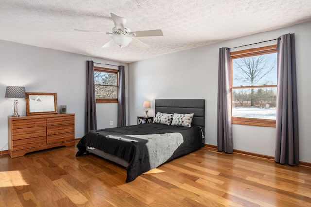 bedroom with a textured ceiling, light hardwood / wood-style flooring, and ceiling fan