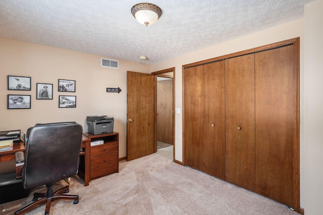 carpeted home office featuring a textured ceiling