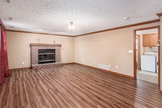 unfurnished living room featuring dark wood-type flooring, a textured ceiling, washer / dryer, and crown molding