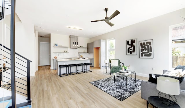 living room featuring sink, a wealth of natural light, ceiling fan, and light wood-type flooring