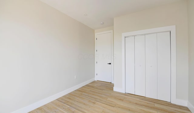 unfurnished bedroom with a closet and light wood-type flooring