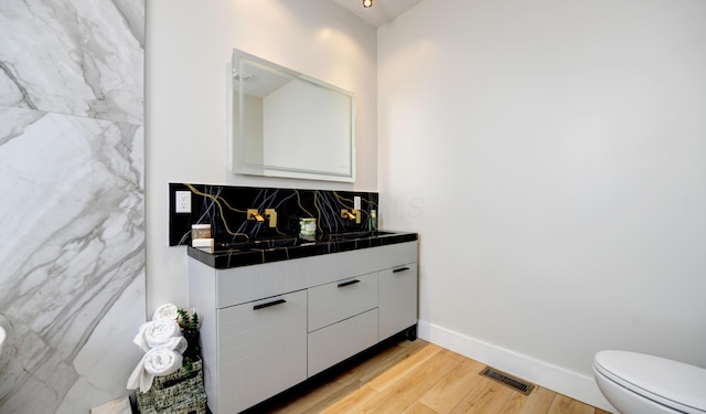 bathroom with vanity, toilet, wood-type flooring, and backsplash