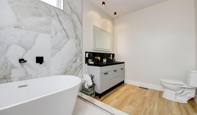 bathroom featuring hardwood / wood-style flooring, vanity, a bathing tub, and toilet