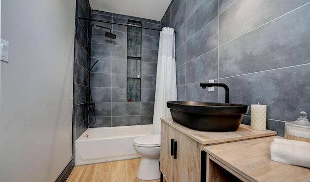 full bathroom with tile walls, vanity, wood-type flooring, shower / bath combination with curtain, and toilet