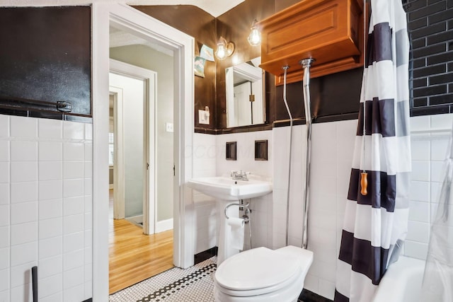 full bathroom featuring shower / bath combination with curtain, sink, wood-type flooring, tile walls, and toilet